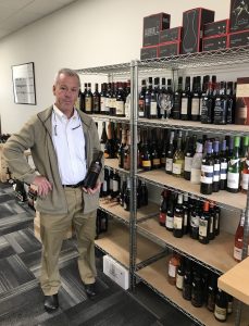 Ed Schlich a wine educator and owner of Oly Wines in Tumwater, standing buy a rack of shelves full of bottles of wine