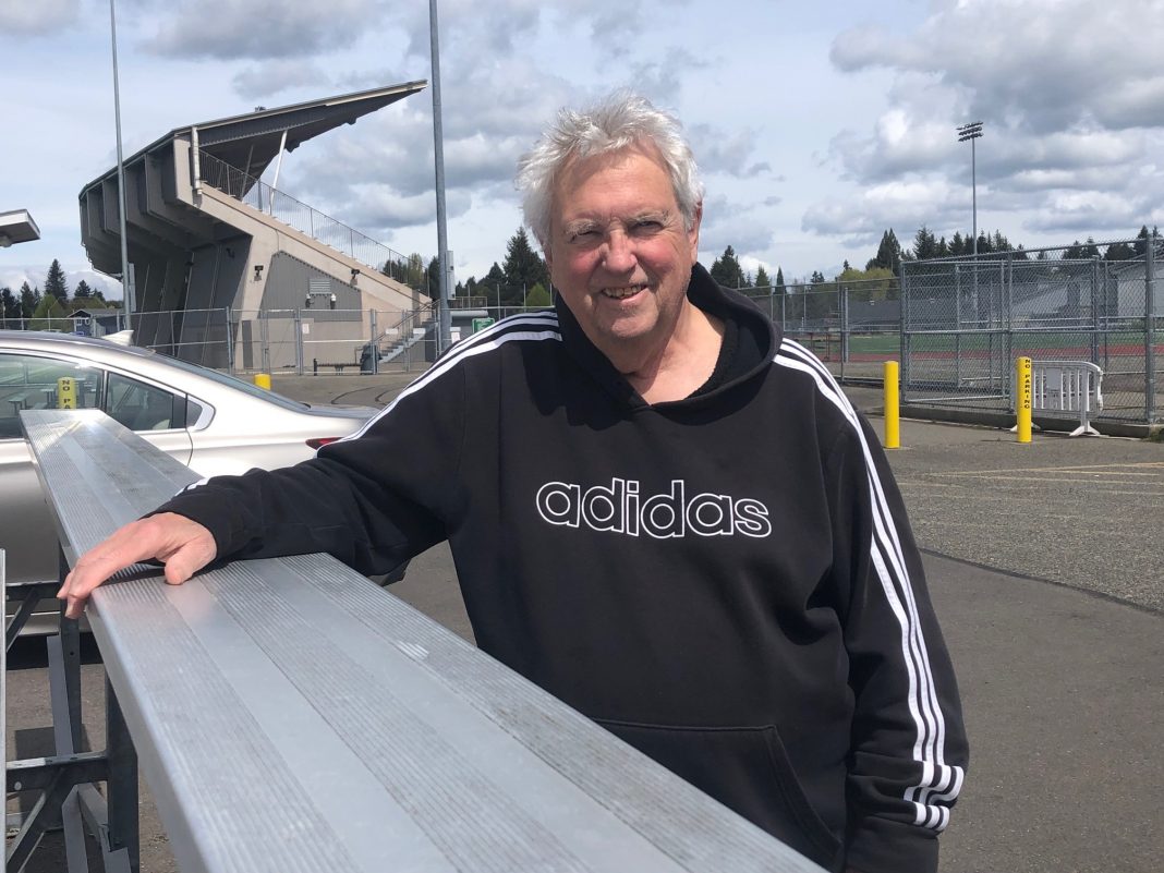 Don Craig standing at the back of metal bleachers with his hand on the top one