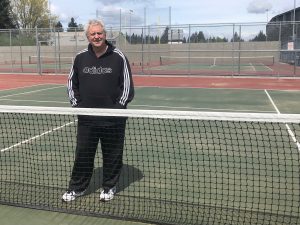 Don Craig standing on a tennis court by the net