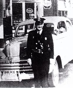 Punch McArthur in uniform in front of Tenino's new 1946 Ford police car.