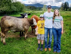 Hicks children with a few of their steers in the background on their farm