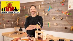 Rick Hartman standing with a bunch of his wooden toys