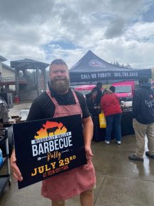 man holding Nisqually Valley Barbecue Rally sign