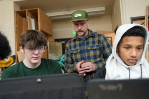 Instructor Chad Carignan helps student Nicholas Haunts-Davis make sure his files are submitted correctly for 3D printing.