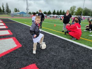 kid on a football field with a soccer ball at Yelm's Day of Champions