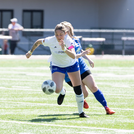 Delaney Smith of the Oly Town Artesians kicking soccer ball on field