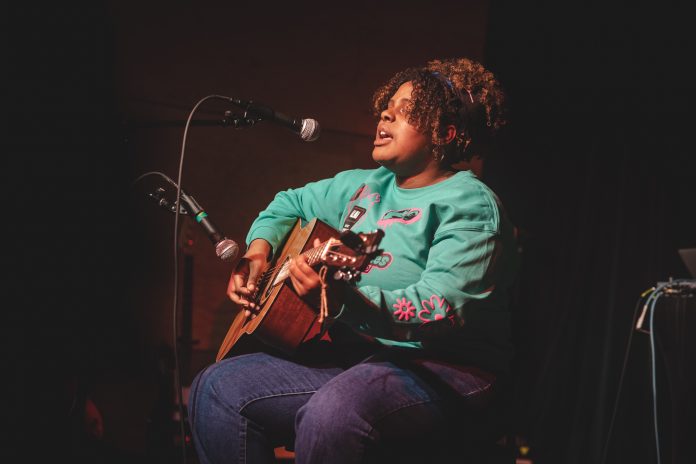 Victoria Standoak playing a guitar with The Bridge Music Project