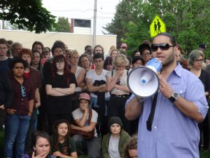 Jose Gutierrez Jr. with a megaphone speaking outside to a crowd