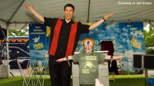 Magician Jeff Evans with a child on stage doing a trick 