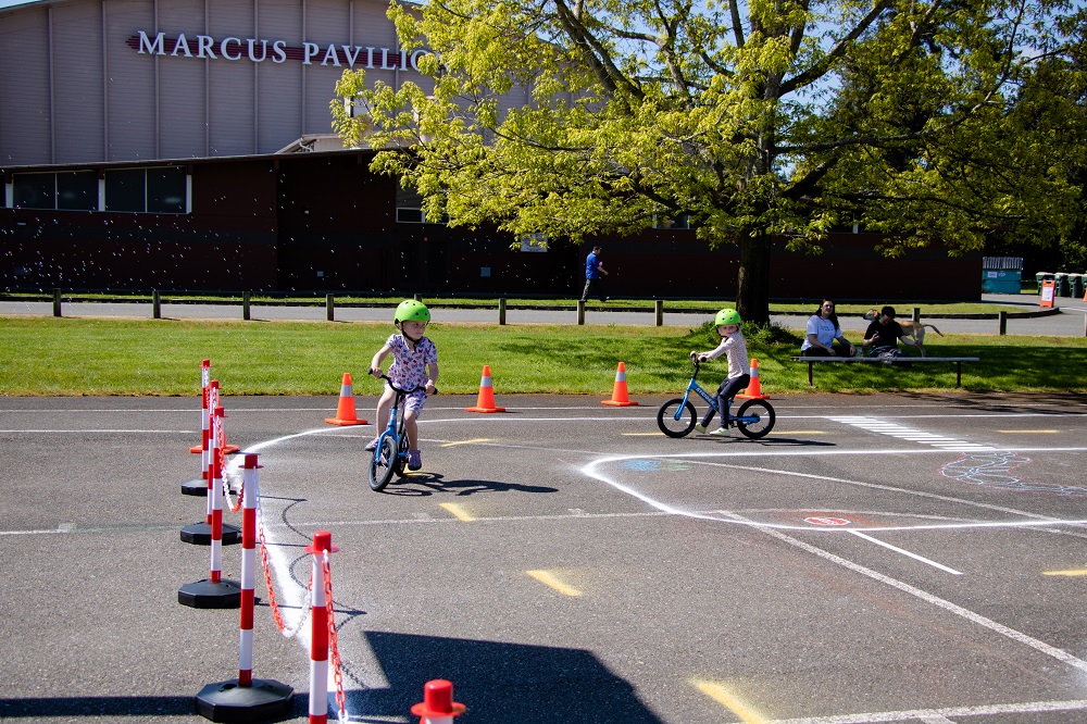 two kids on bikes riding down fake streets made with chalk lines at Olympia Bike Rodeo