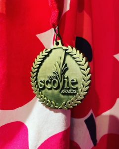 Scovie Award against a red, white and pink flag
