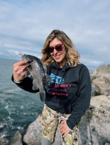 Jess Caldwell holds a black sea bass while Westport Jetty Fishing