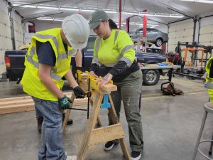 student and instructor cutting with an electric saw at Yelm High School Construction Camp