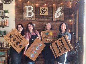four women holding wood signs they created