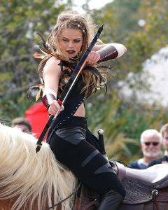 women on horse back shooting an arrow