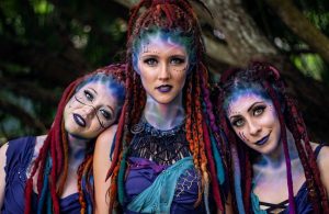 three women in blue body paint with red dreaded hair
