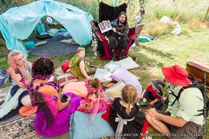 person reading to a group of kids under a fairy tent at the Washington Midsummer Renaissance Faire