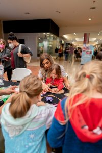 adults and kids doing crafts at a table at Capital Mall