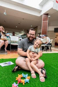 man with a young boy sitting on his lap on the ground at Capital Mall