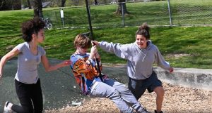 three kids playing on a swing