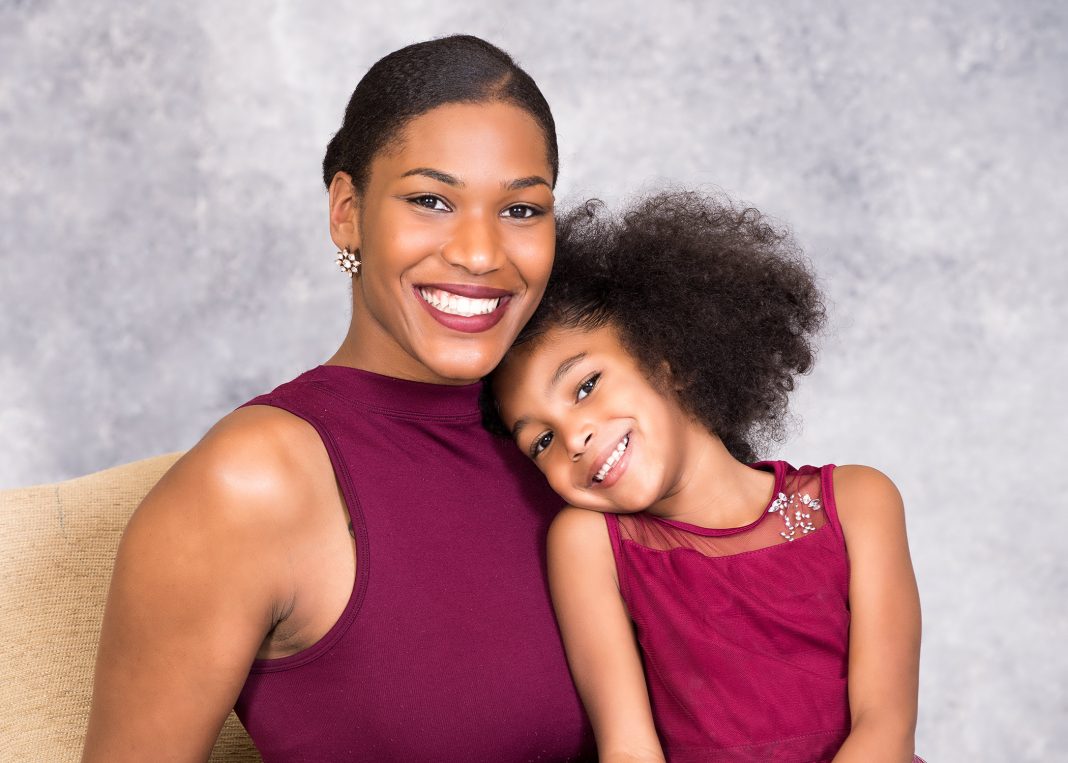 a woman and a young girl in matching outfits pose for a professional photo