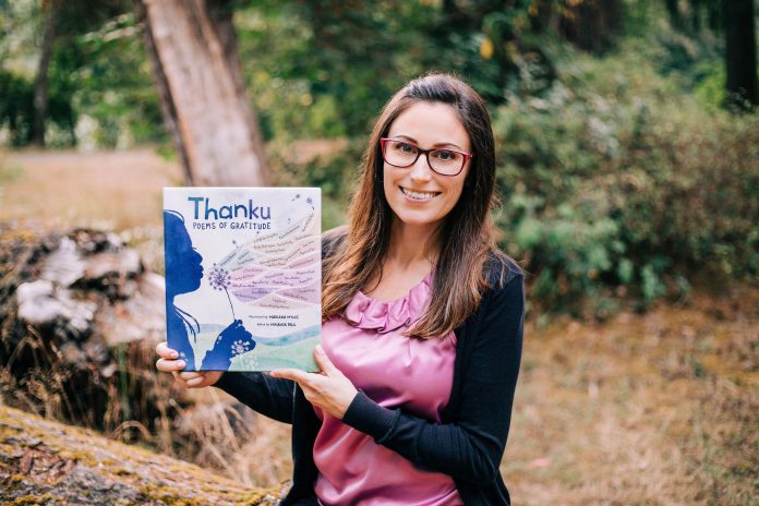 Jamie McGillen holding a book with her poetry published in it