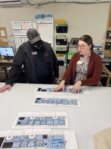 General Manager Jeremy Scott discusses ad designs with Graphics Manager Megan Gravelle while standing at a large table