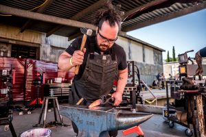 man pounding steel on an anvil