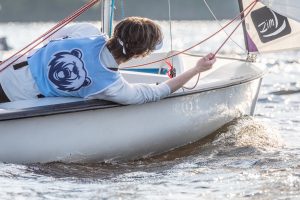 high school sailing team member leaning out over boat