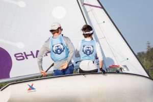 two high schoolers sitting on a sailboat with backs to the camera