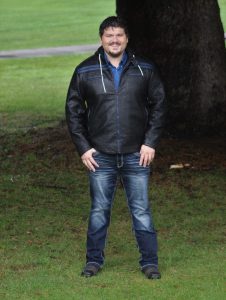 Hayden Hoage, Loan Originator with PrimeLending, standin by a tree