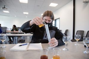 college student at a science lab pouring a liquid into a beaker at SPSCC's brewing program