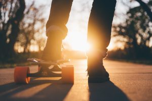 silhouette of a skateboard with one foot on the board at sunset