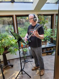 Tom Dyer standing up and recording with his guitar