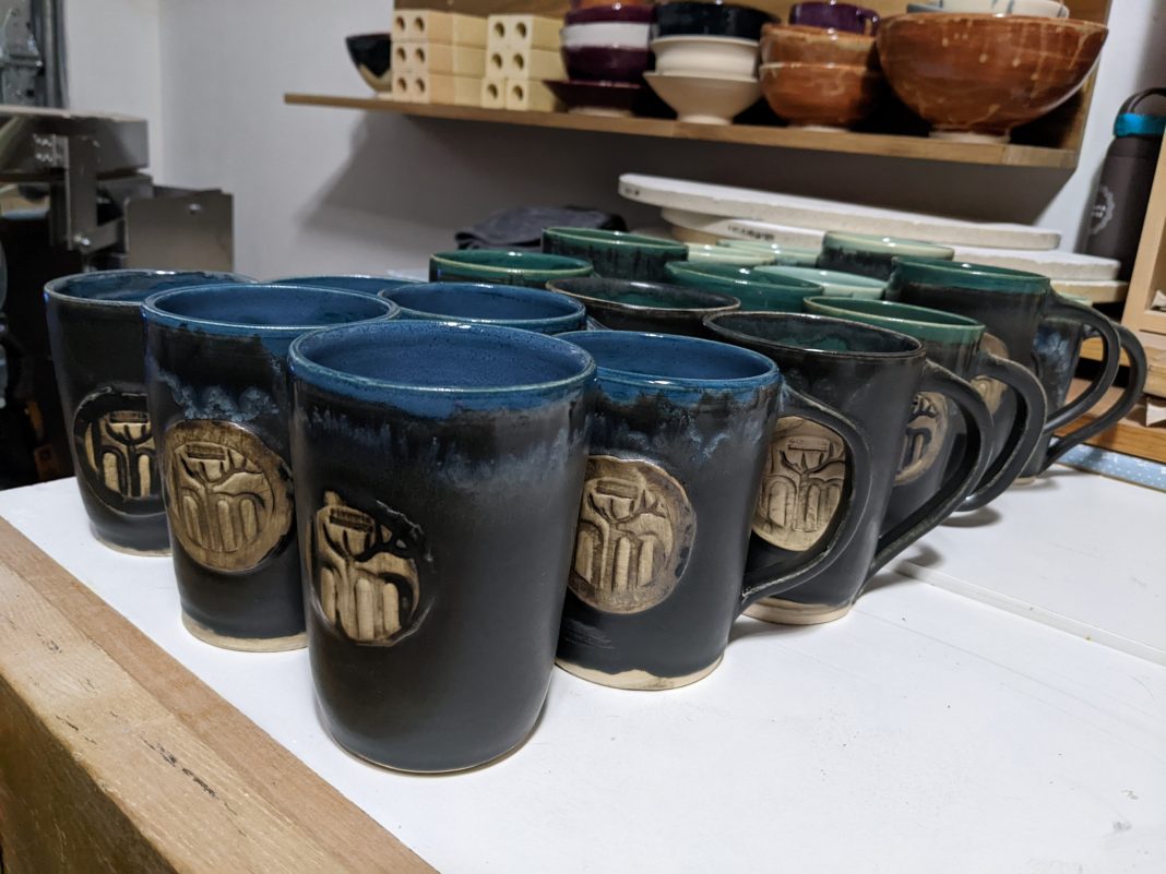 group of blue-green Oktoberfest ceramic mugs on a white table