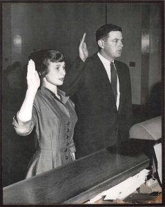 black and white photo of Herbert and Carol Fuller standing in court with right hands raised