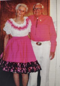 John Hurley and wife Bonnie, standing together in matching pink square dancing outfits