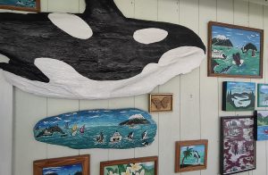 John Hurley artwork: an orca painted on a piece of driftwood hanging on a wall