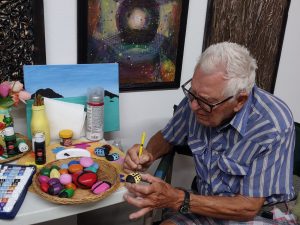 John Hurley painting rocks at a table