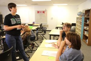 a group of students at desks with a teacher in front of them