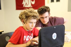 two teen students looking a laptop