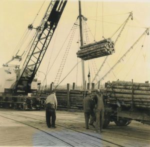 timber being put onto a boat by crane at the Port of Olympia in the 1950s