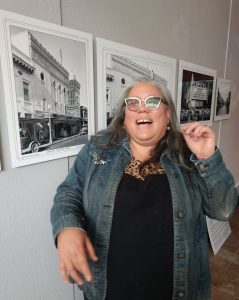 Revival Motors & Coffee Co. owner Audre Henley standing next to a wall of old photographs