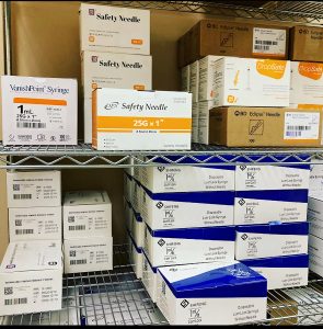metal shelves full of boxes of needles and syringes