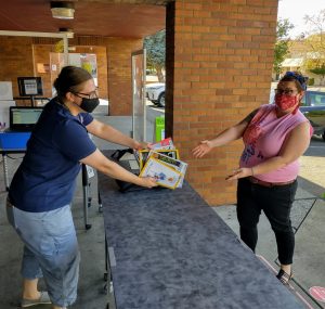 A woman picking up a book outside at a Timberland Regional Library low-touch station