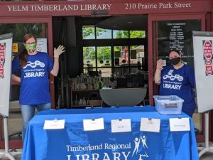 people standing at a table outside a Timberland Regional Library checking in books during COVID