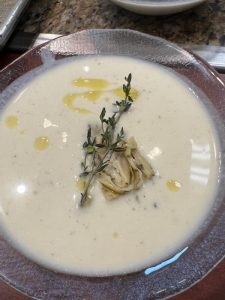 a bowl of soup with artichoke heart garnish