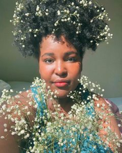 Eunice Ndungu headshot with baby's breath flowers in her hair and in front of her