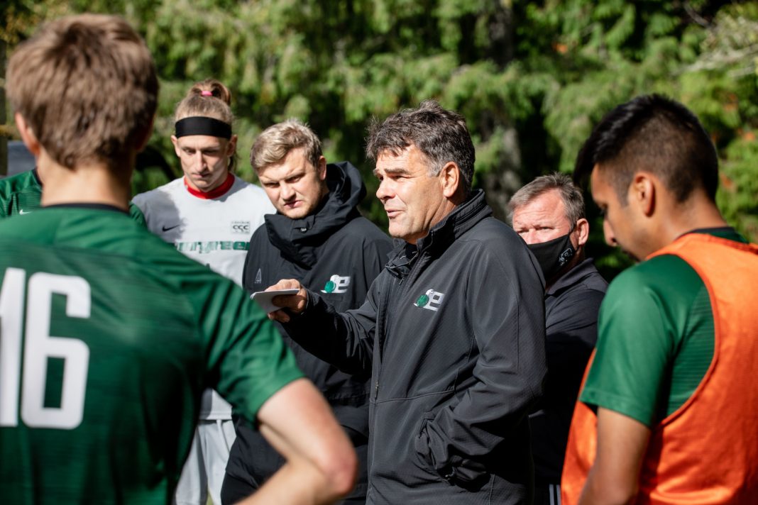 The Evergreen State College men's soccer coach talking to his team on the field during a match