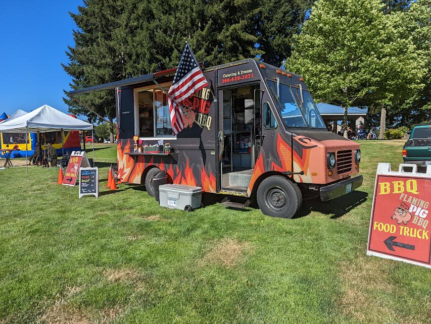 Flaming Pig BBQ food truck in a grass field